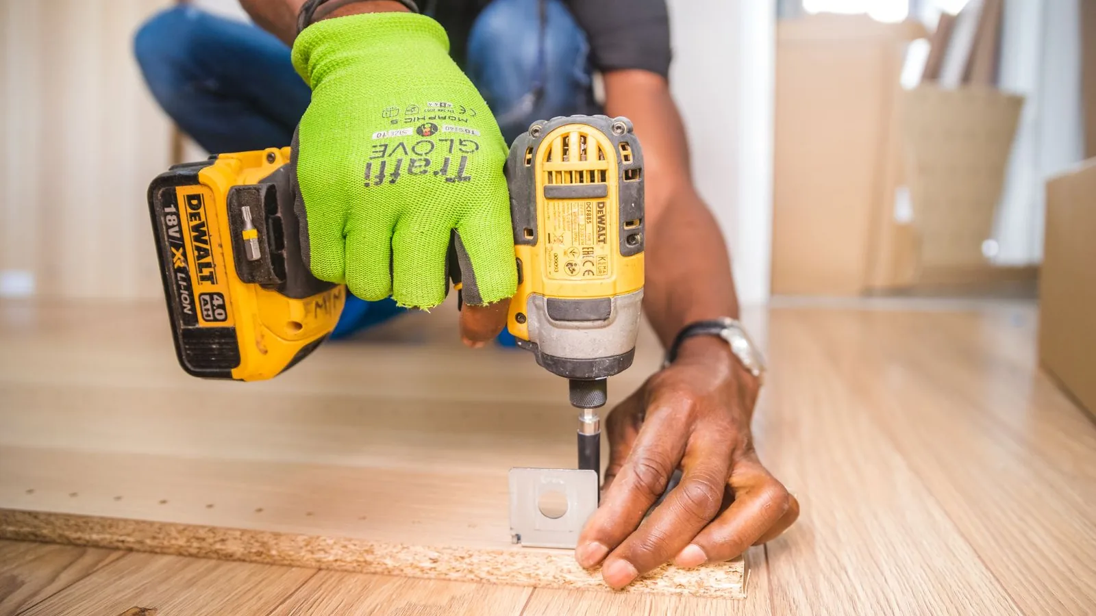 A contractor fixing a bracket to a timber floor with a cordless driver